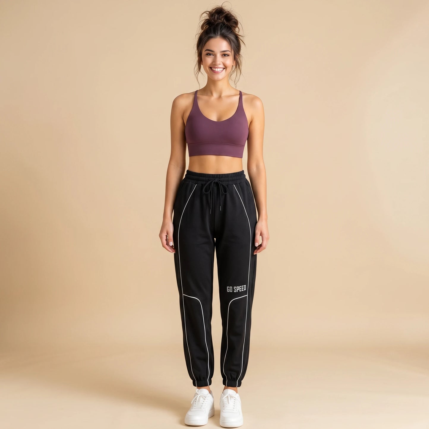 Woman in black high-waist loose-fit joggers with white side piping, tapered cuffed sweatpants, front view