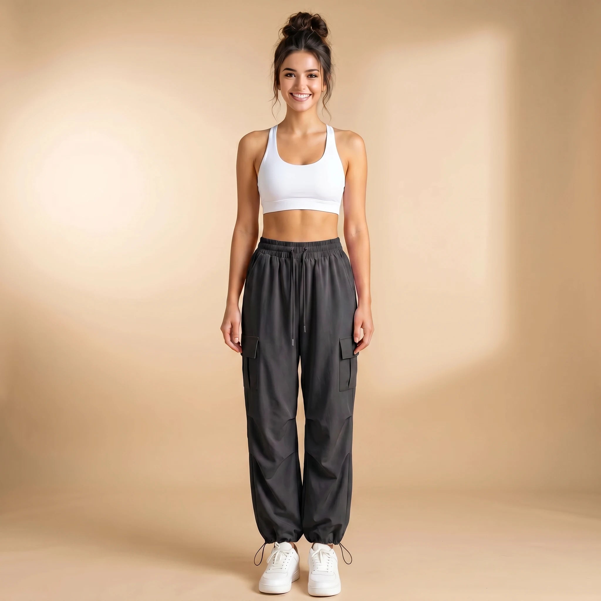 Woman in deep grey high-waist cargo joggers with flap thigh pockets, cuffed loose-fit pants, front view