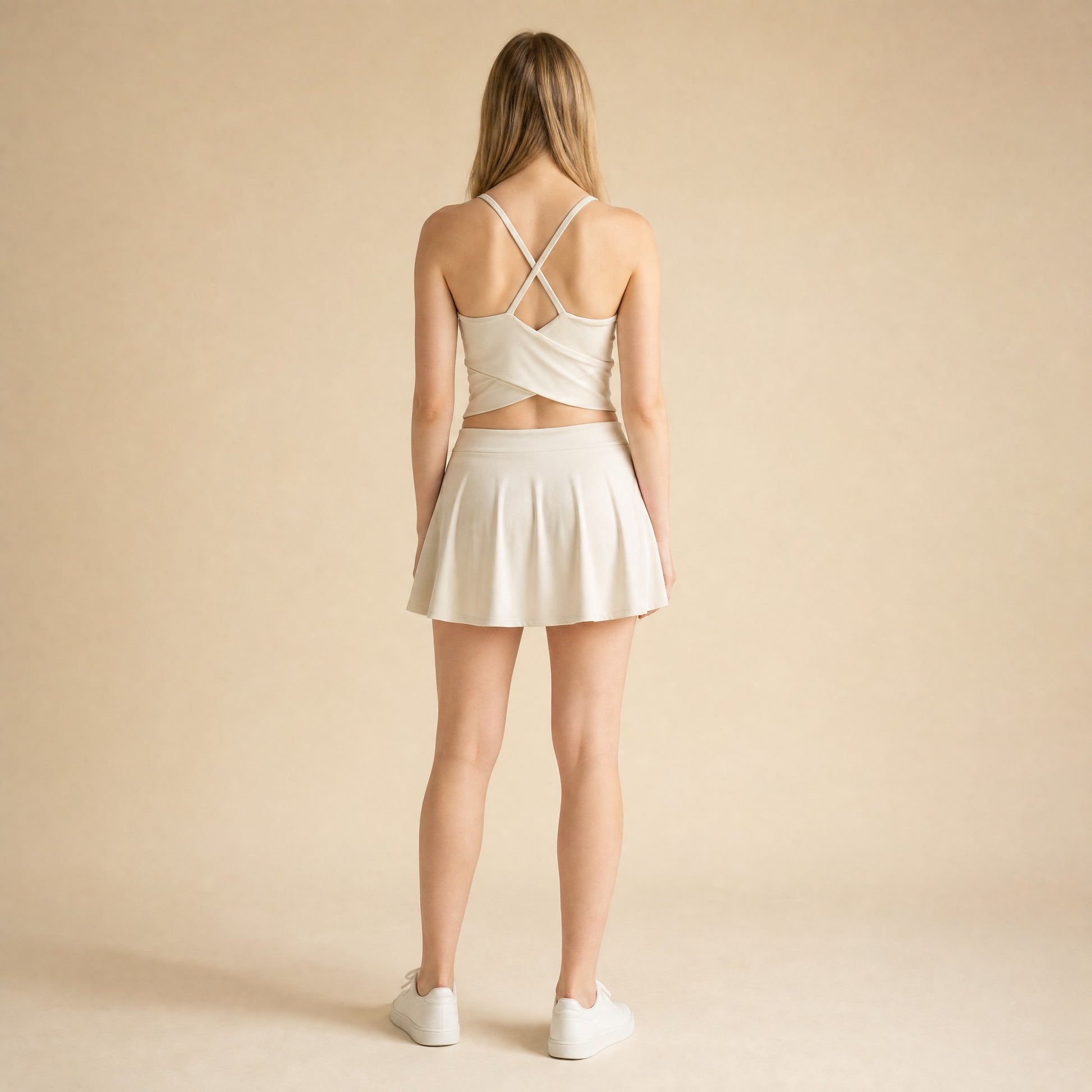 Strappy cross-back yoga bralette in beige showing crossing straps and wrap-style back hem, back view