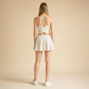Strappy cross-back yoga bralette in beige showing crossing straps and wrap-style back hem, back view