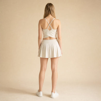 Strappy cross-back yoga bralette in beige showing crossing straps and wrap-style back hem, back view