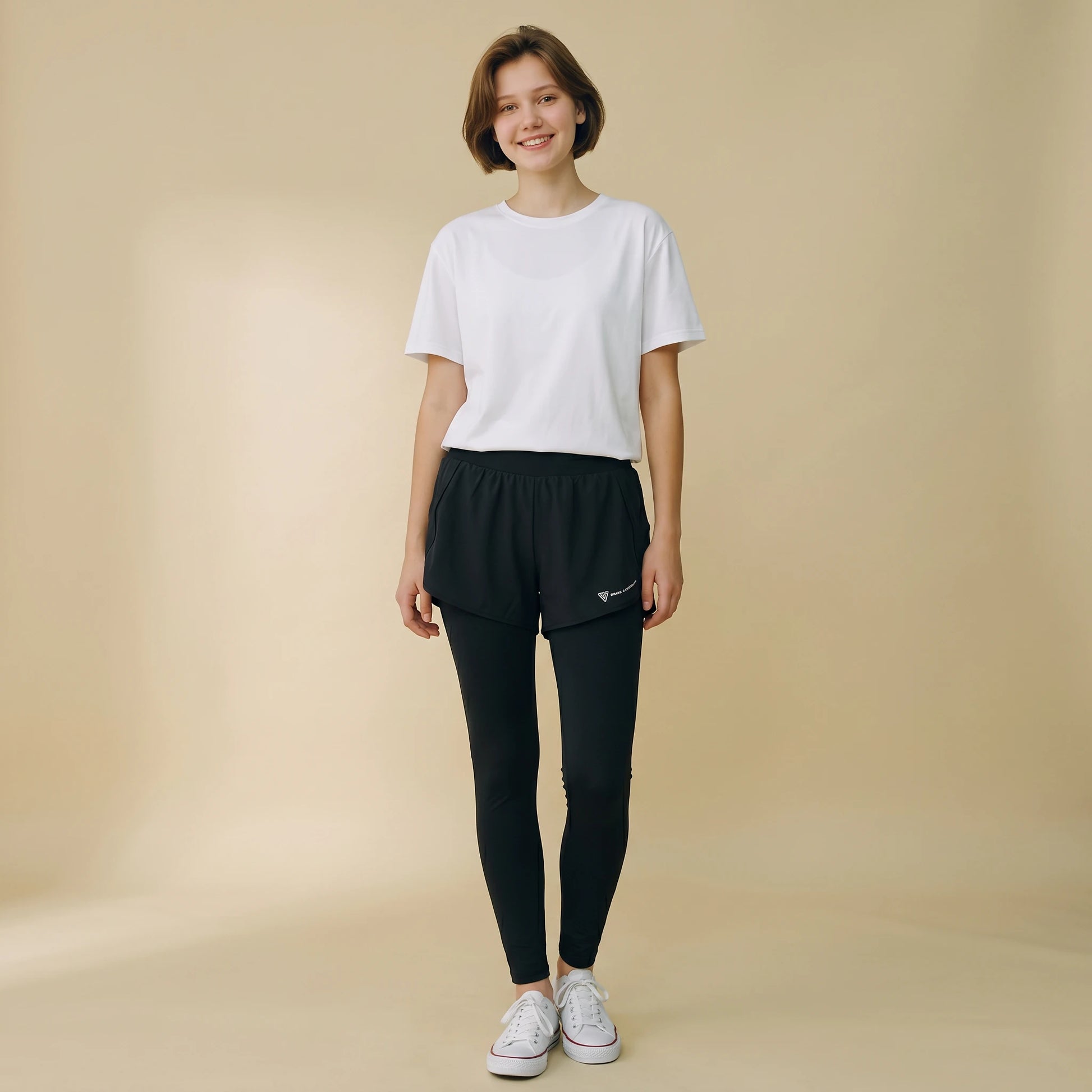 Woman in black 2-in-1 high-waist leggings with built-in overlay shorts, full-length yoga pants, front view