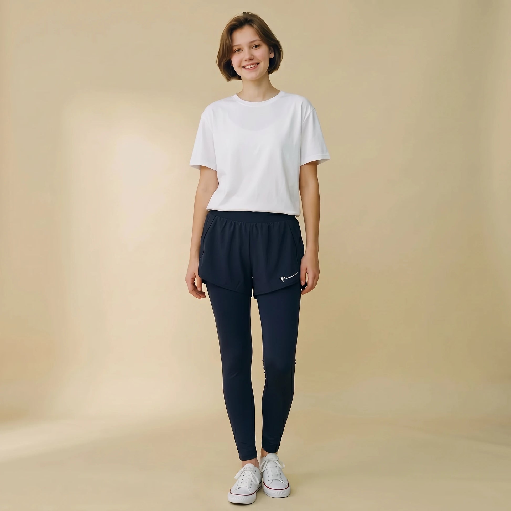 Woman in navy blue 2-in-1 high-waist leggings with built-in overlay shorts, full-length yoga pants, front view