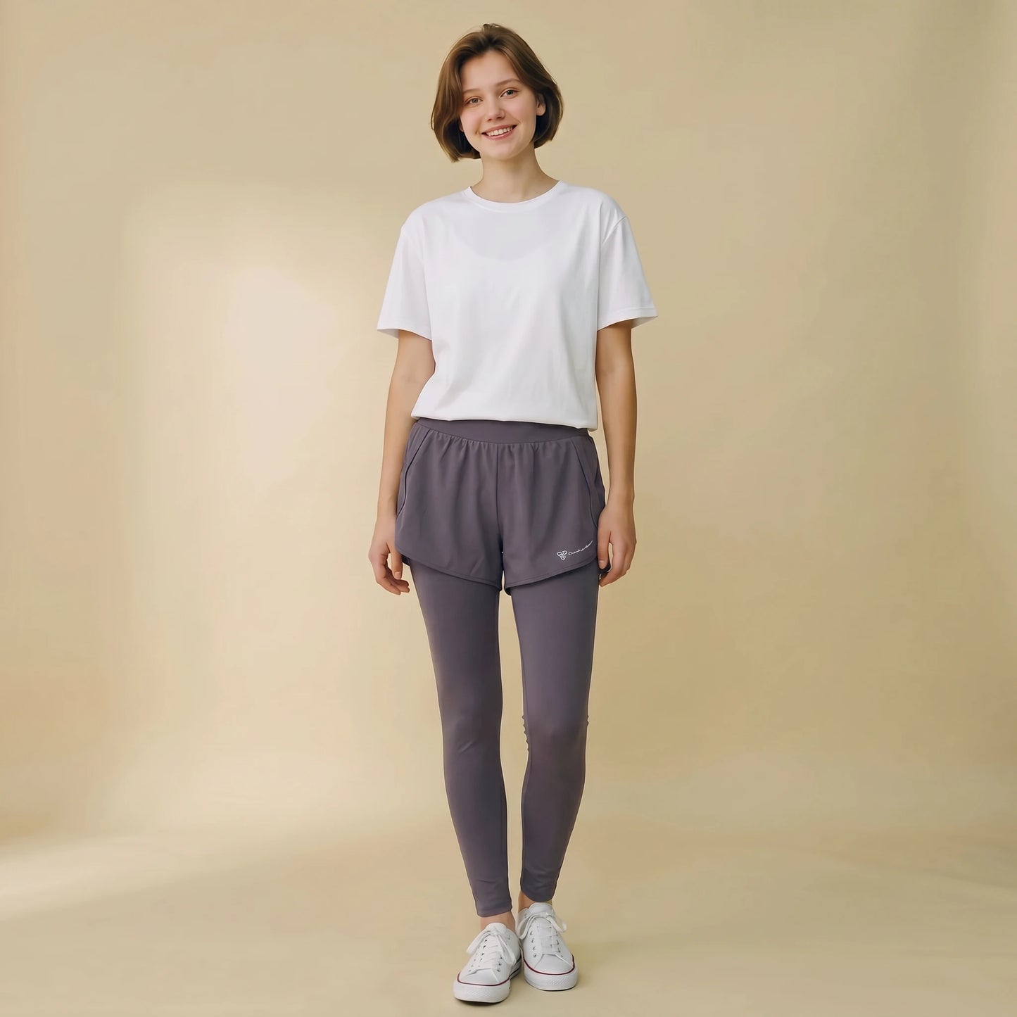 Woman in charcoal 2-in-1 high-waist leggings with built-in overlay shorts, full-length yoga pants, front view